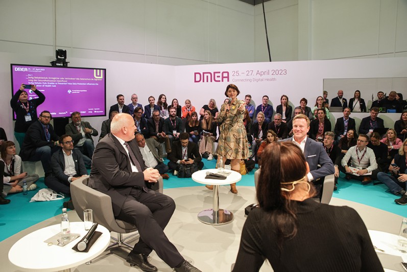 Drei Gäste, eine Moderatorin und Zuschauer auf der DMEA 2023. Drei Gäste, eine Moderatorin und Zuschauer auf der DMEA 2023.