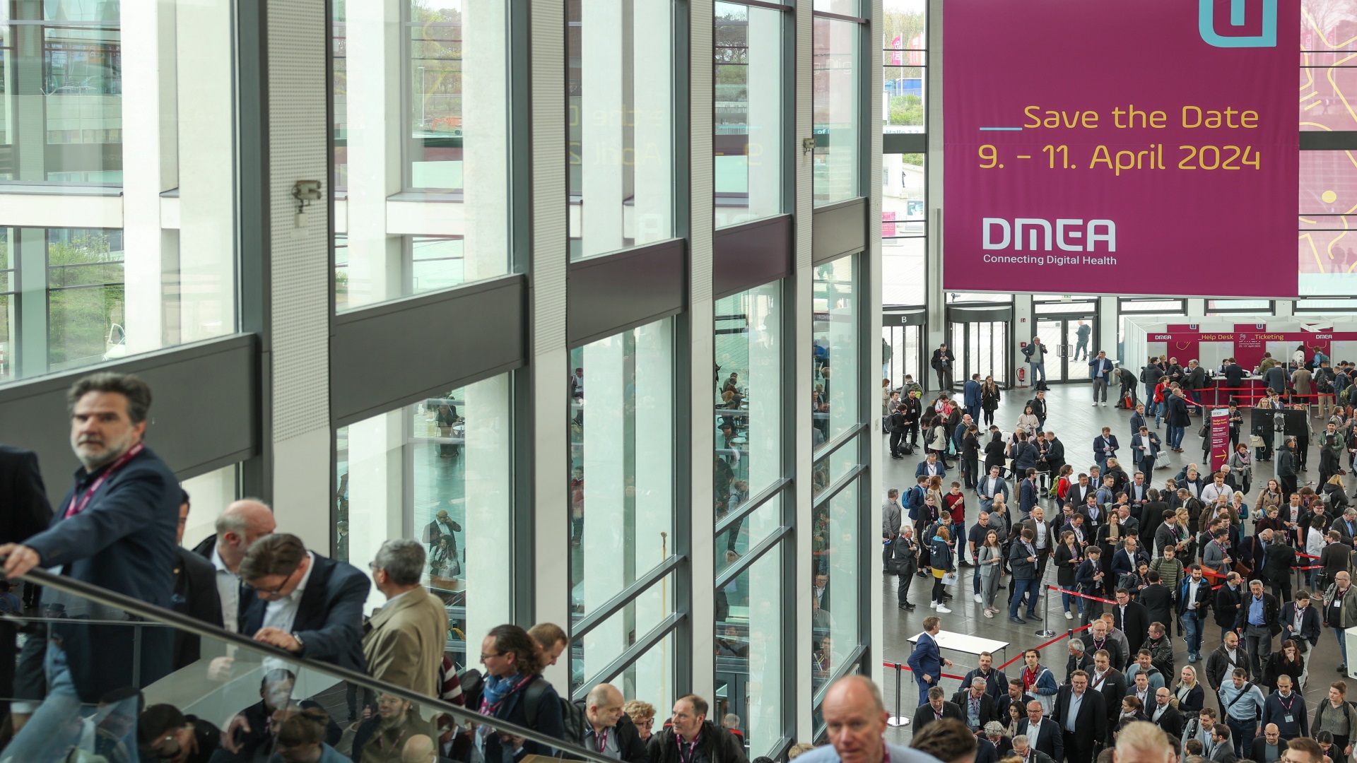 Besucher:innen auf dem Weg in die Messehallen; Save the Date-Schild zur DMEA 2024 Besucher:innen auf dem Weg in die Messehallen; Save the Date-Schild zur DMEA 2024
