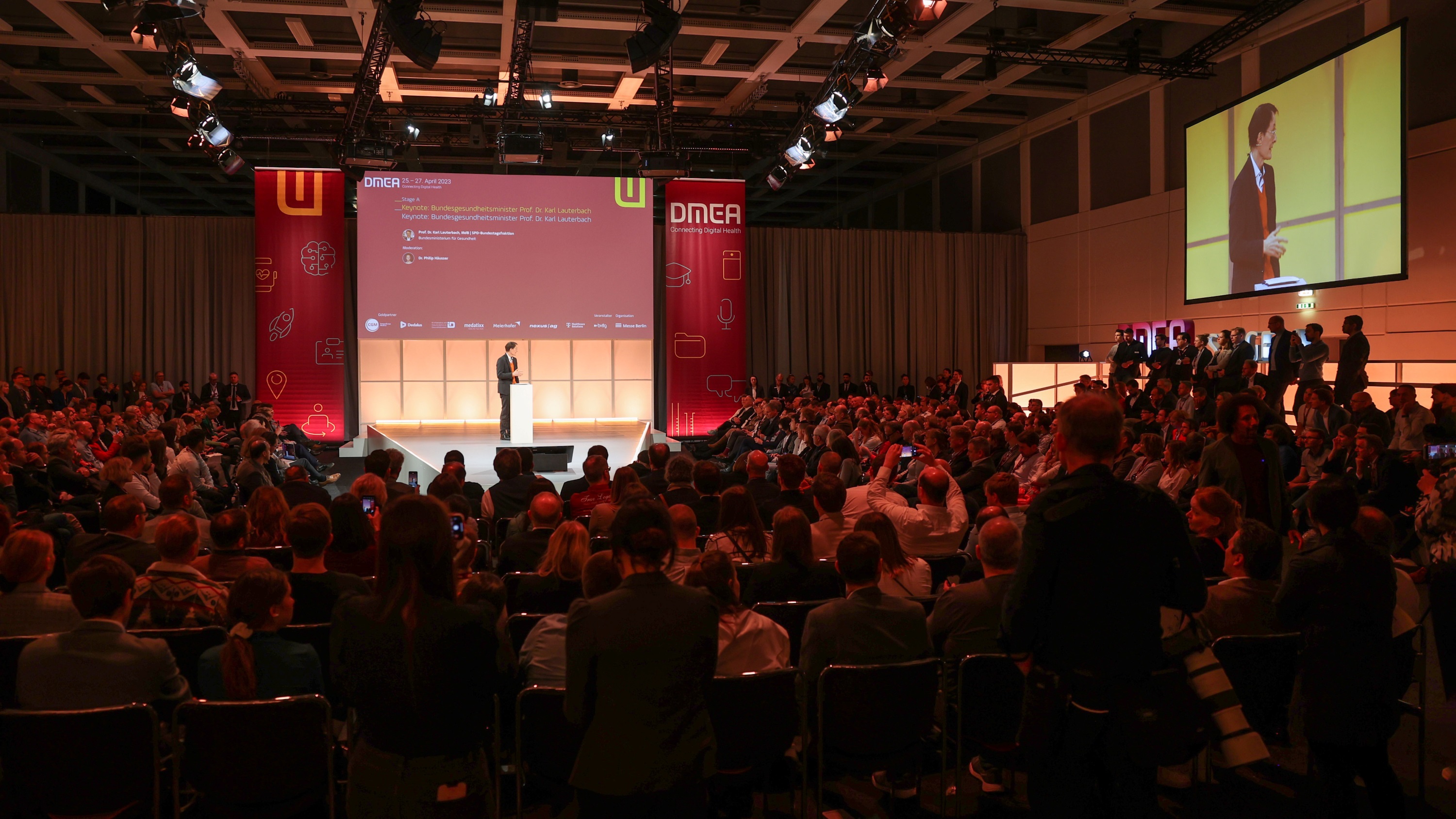 DMEA stage, audience in the foreground, Prof. Dr. Karl Lauterbach onstage in the background 