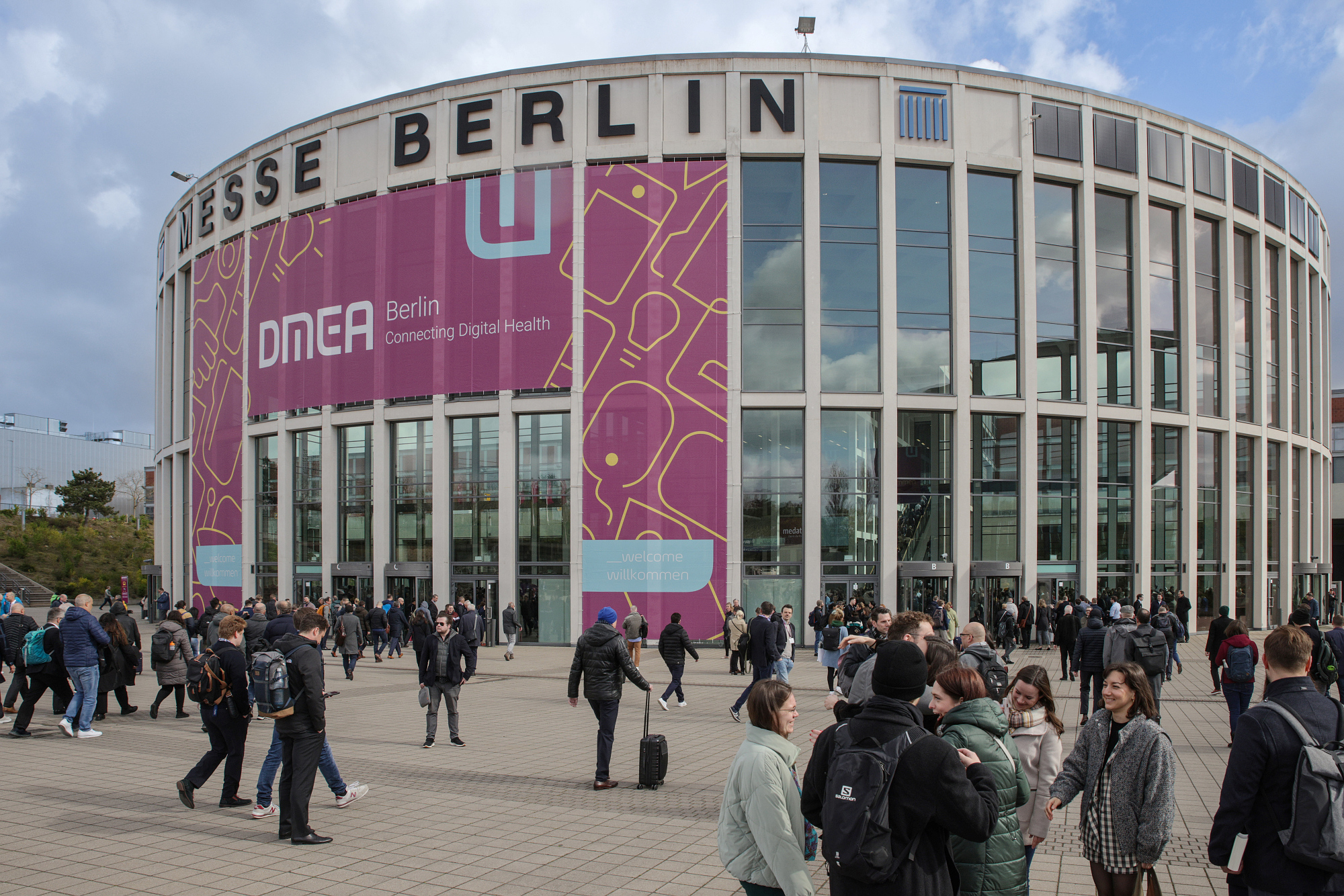 Messe Berlin south entrance, with a large DMEA banner and visitors in the foreground 