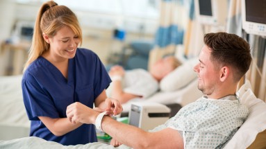 A nurse is putting a patient wristband on a patient.
