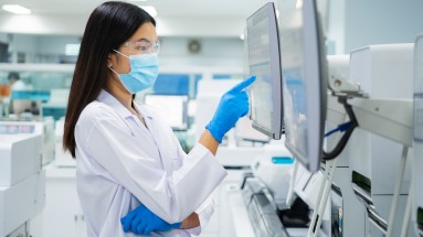 A lab technician points to a screen with her right index finger.