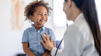 Eine Ärztin, die den Herzschlag eines Kindes mit einem Stethoskop abhört