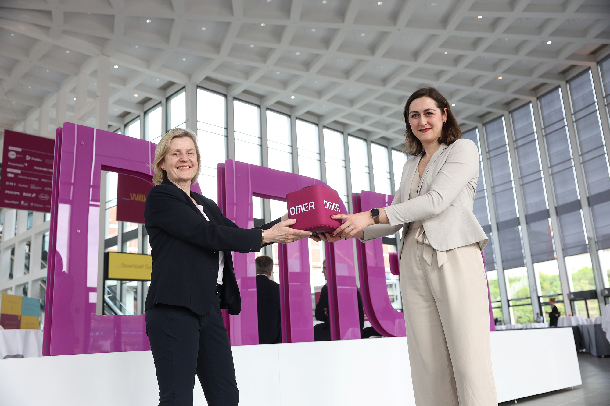 Ursula Baumann and Burcu Dural-Lange in front of the DMEA lettering at the South Entrance of Messe Berlin 
