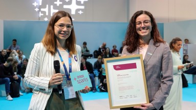 Presenter on the left with microphone and DMEA sparks card, winner Carina Arnberger on the right holding the framed DMEA sparks 