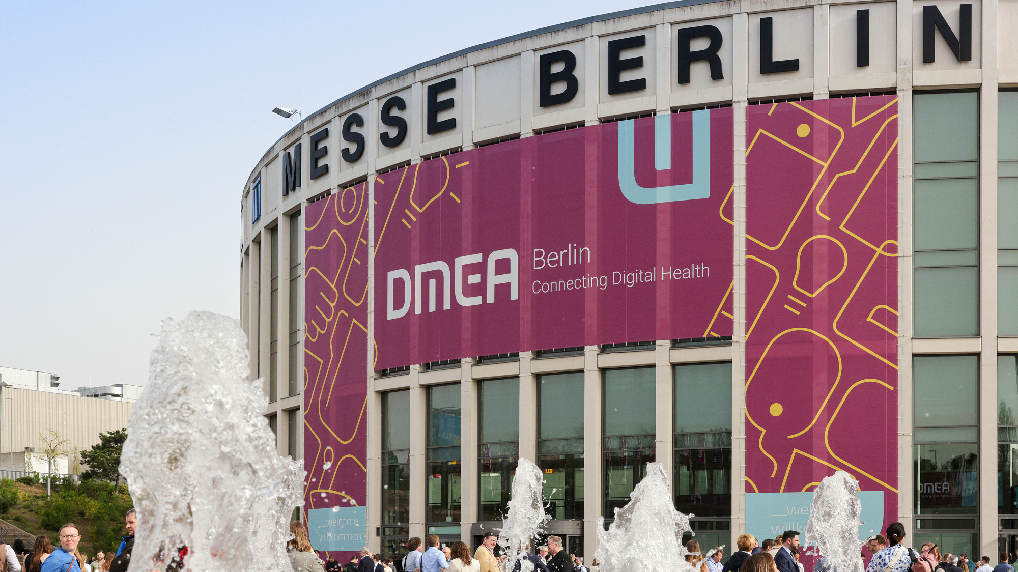 Ansicht des Südeingangs der Messe Berlin mit dem DMEA-Megabanner im Hintergrund und Wasserfontänen im Vordergrund